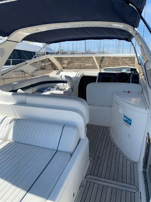 Interior of a luxury boat with white seating, a steering console, and a first aid kit visible on the right.